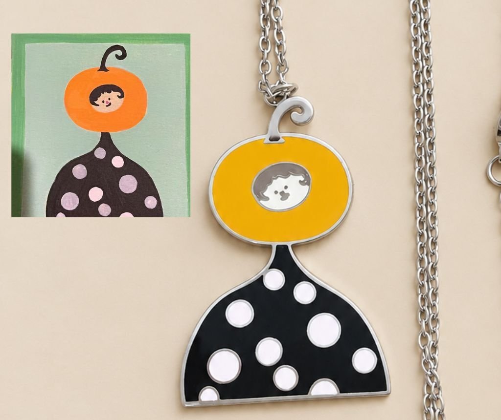 Close-up of the pumpkin-head pendant beside the original drawing it was traced from
